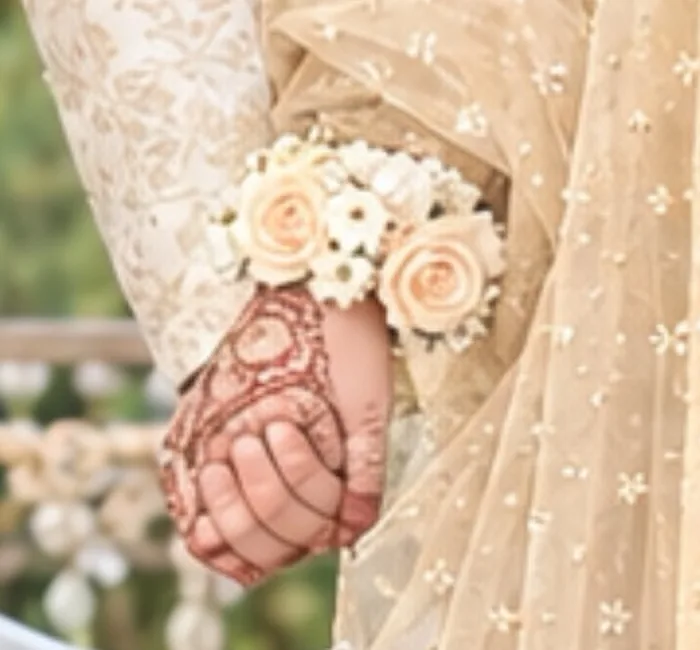 Bride's hennaed hand with a rose gajra, held by the groom